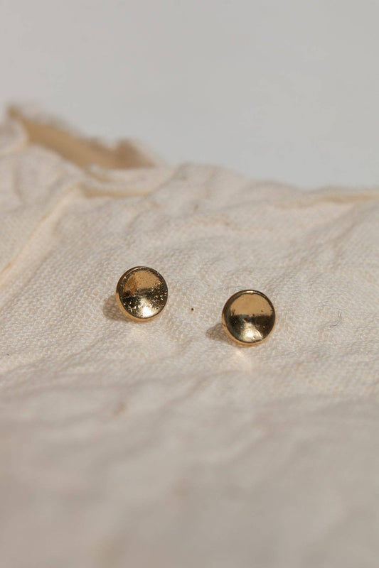 Pair of gold stud earrings on a textured beige surface