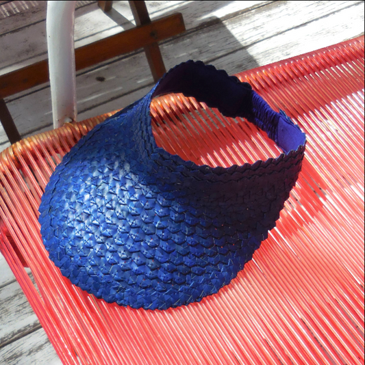 Blue visor on a red woven chair with wooden floor background