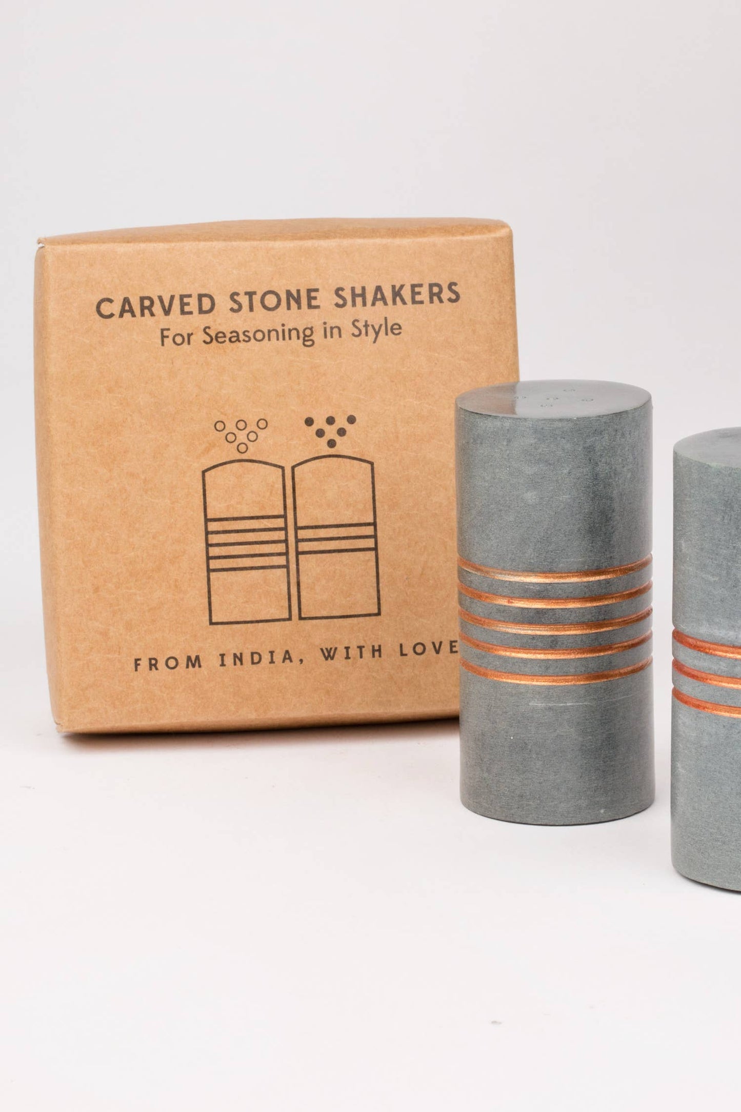 Carved stone shakers with a cardboard box on a white background
