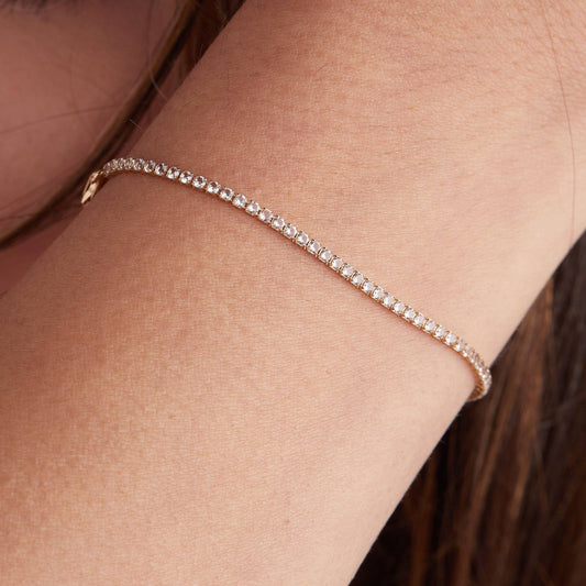 Rose gold bracelet on a person's wrist with a blurred background