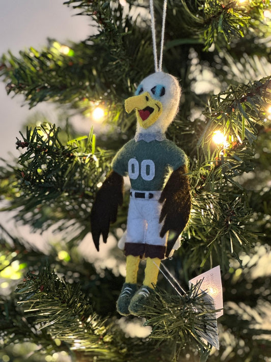 Eagle-shaped Christmas ornament in a green jersey hanging on a tree.