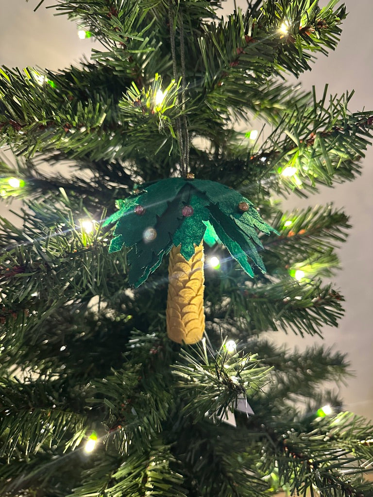 Decorative palm tree ornament on a Christmas tree with lights.