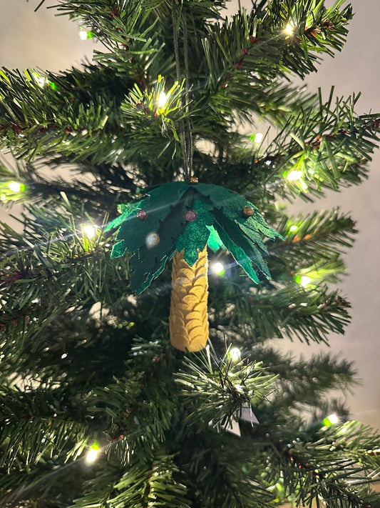 Decorative palm tree ornament on a Christmas tree with lights.