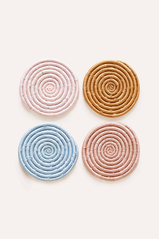 Four circular woven coasters in pastel colors on a white background