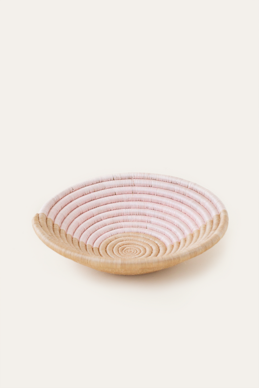 Round woven basket with pink top and natural base on a white background