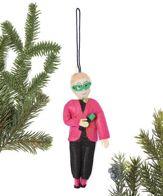 Ornament of a person in a pink jacket and green glasses holding a microphone hanging on a branch with a white background