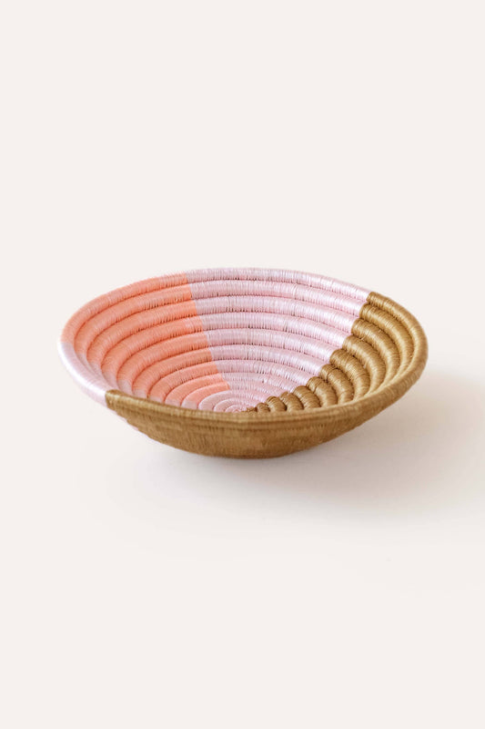 Woven basket with pink and beige gradient on a white background