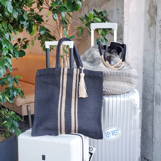 Two woven bags with tassels on a suitcase next to a radiator with 'Key West' label.