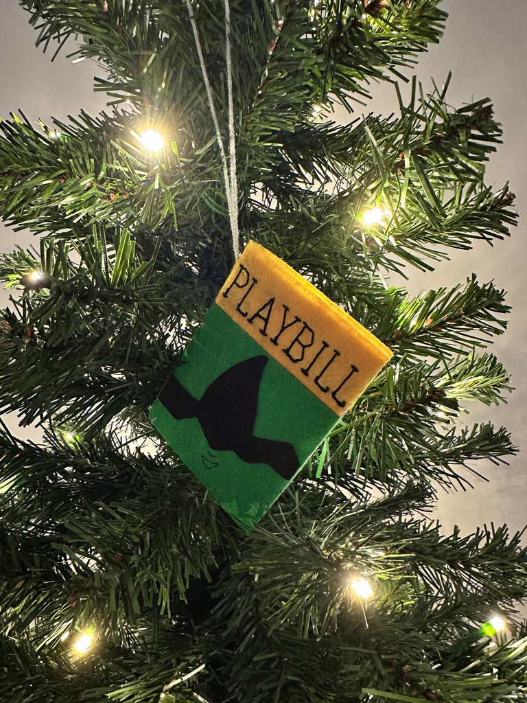 Playbill ornament hanging on a Christmas tree with lights.