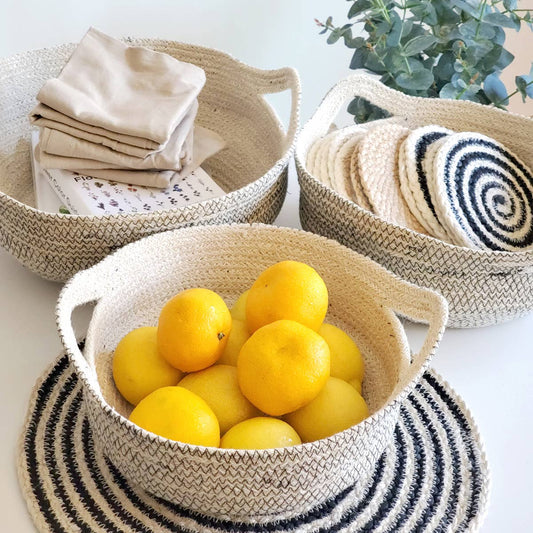 Woven baskets with lemons, fabric, and a plant on a light surface