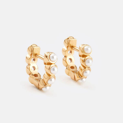 Gold hoop earrings with pearl accents on a light gray background