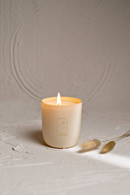 White candle with a flame on a textured beige surface