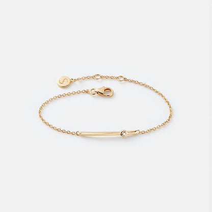 Gold bracelet with a bar design on a light gray background