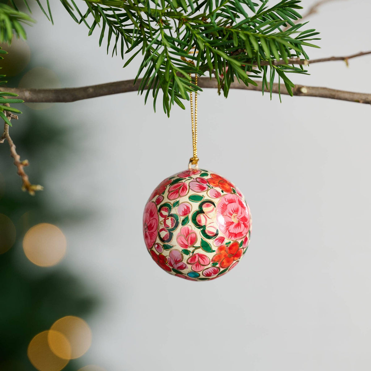Decorative floral ornament hanging on a tree branch with a blurred background