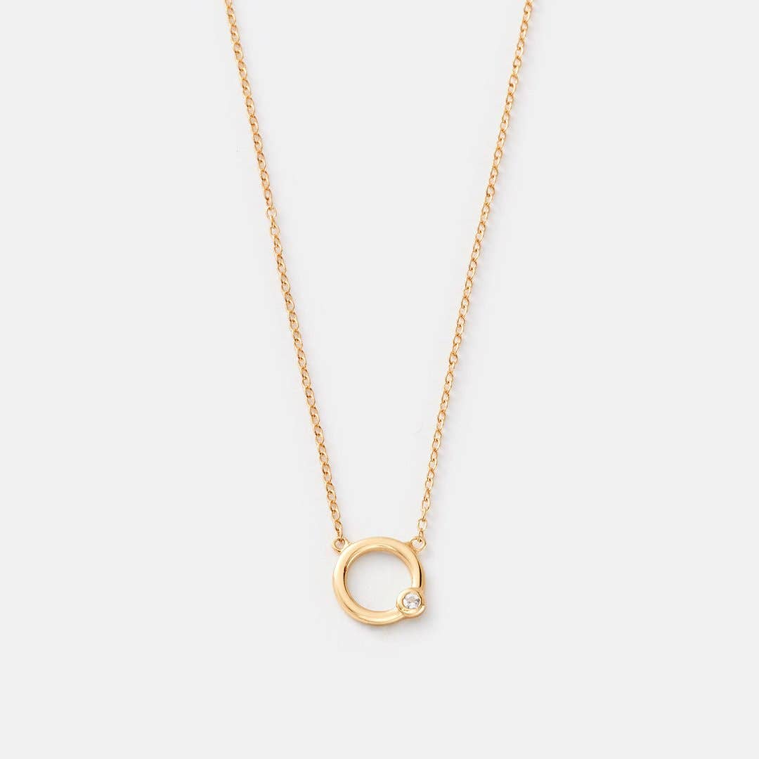 Gold necklace with a small circular pendant on a light gray background