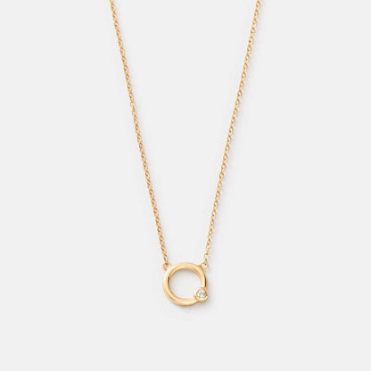 Gold necklace with a small circular pendant on a light gray background
