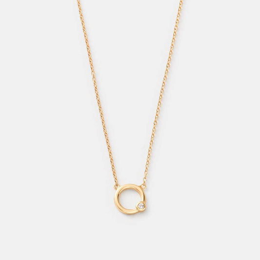 Gold necklace with a small circular pendant on a light gray background