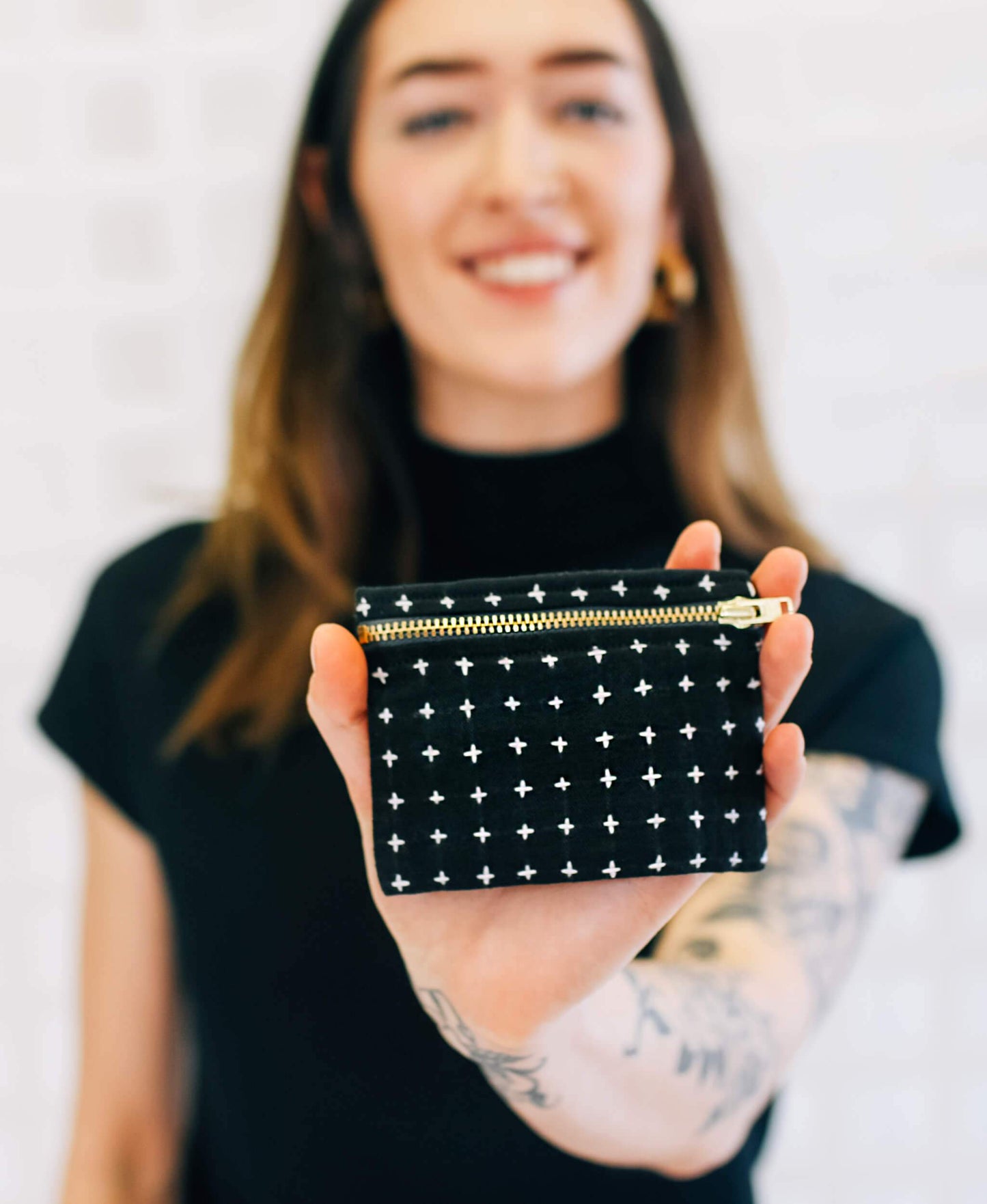 Person holding a black pouch with white star patterns and a gold zipper.