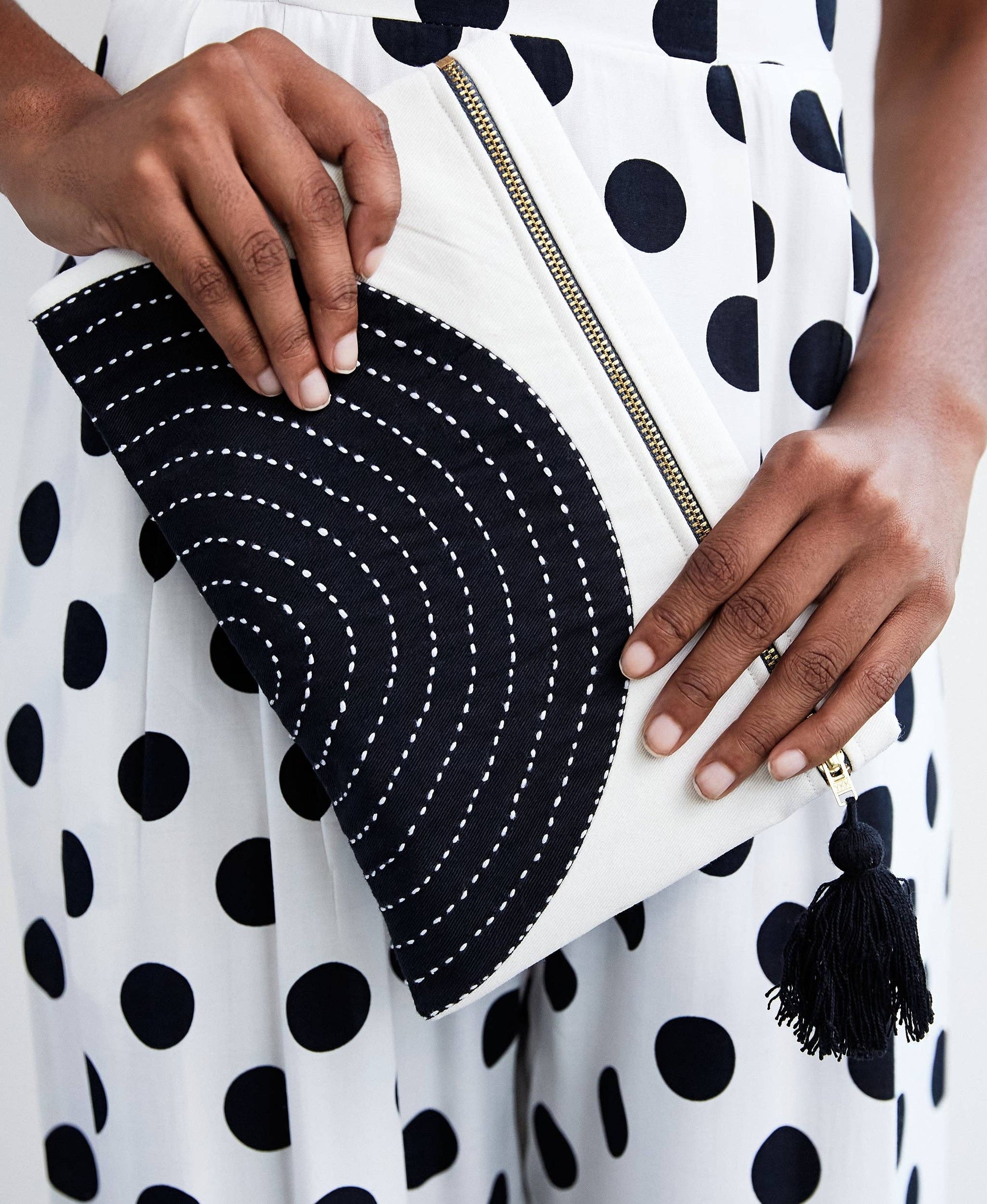 Black and white clutch held by a person wearing a polka dot dress