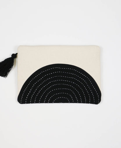 Beige pouch with black circular design and tassel on a white background