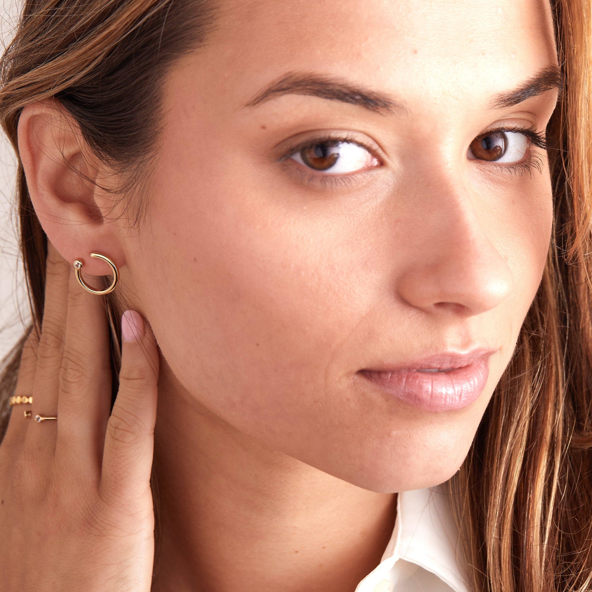 Close-up of a woman wearing a gold hoop earring with a neutral background