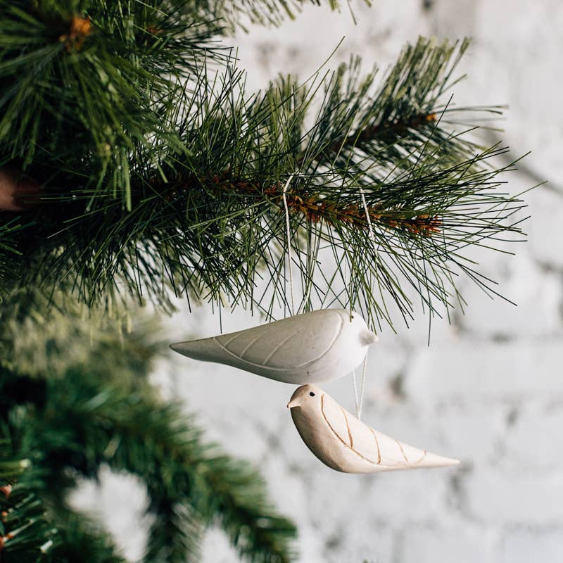 Decorative ceramic dove ornament hanging from a Christmas tree branch.