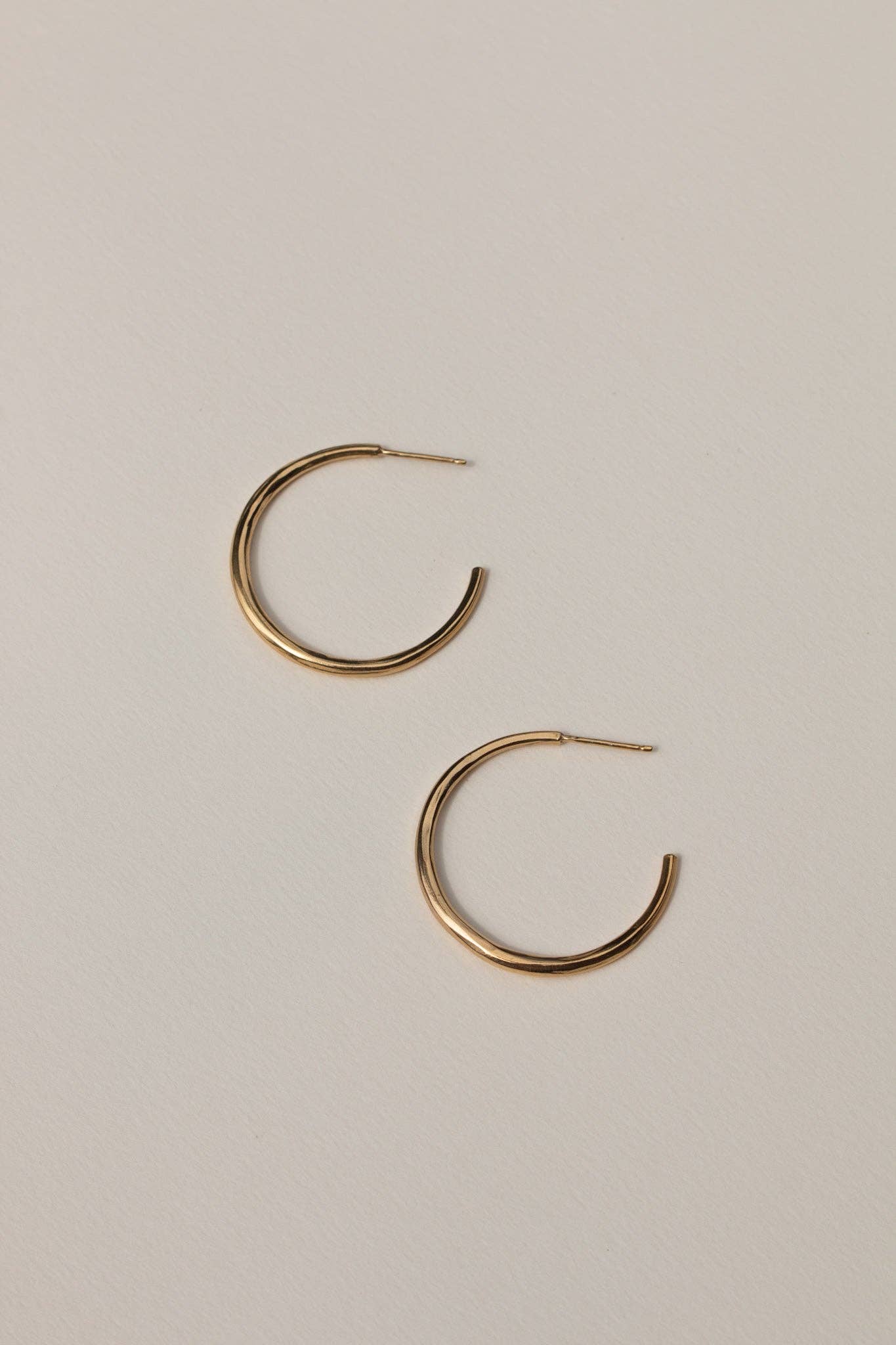 Gold hoop earrings on a beige background