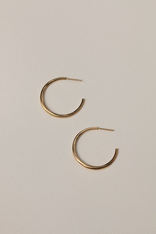 Gold hoop earrings on a beige background