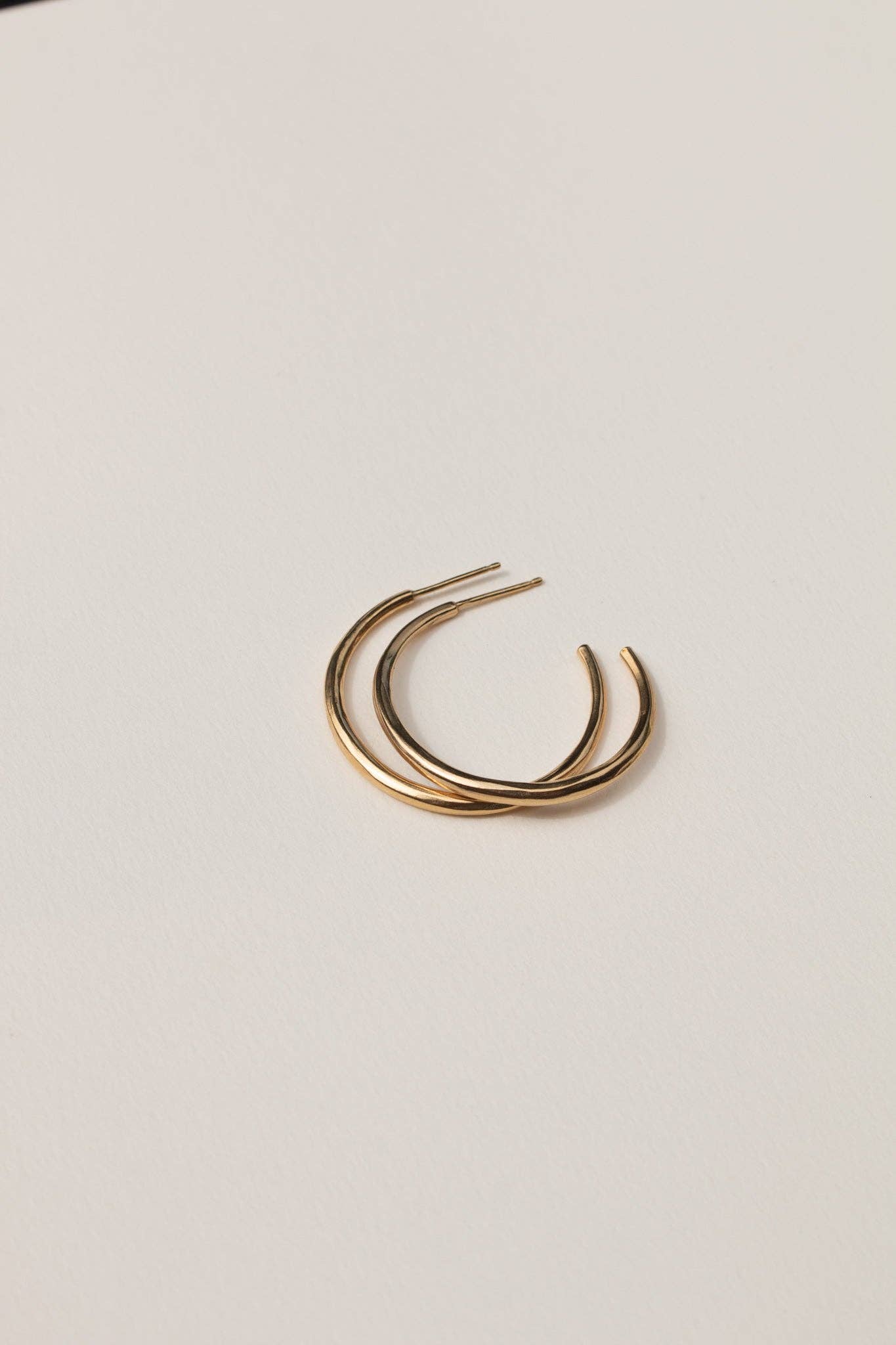 Gold hoop earrings on a light beige background