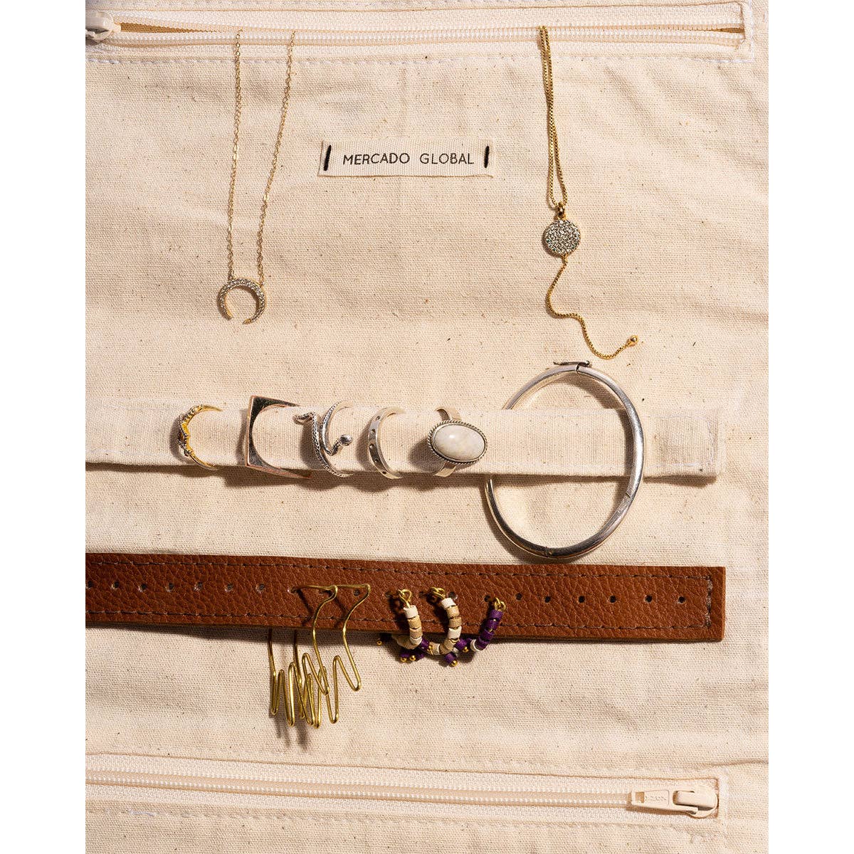 Jewelry set including necklaces, earrings, and a belt on a Mercado Global branded bag.