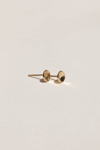 Gold earring on a light gray background