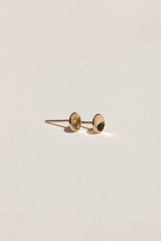 Gold earring on a light gray background