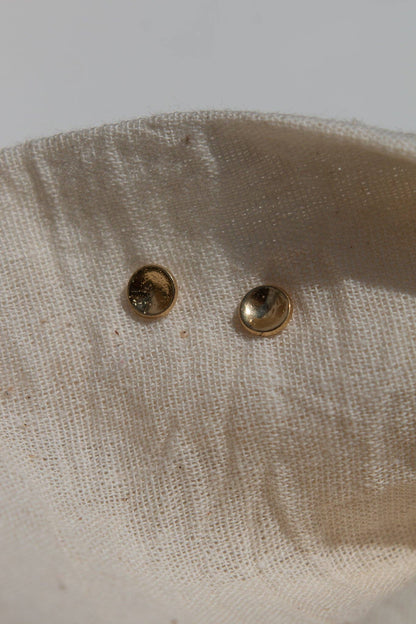 Two gold studs on a beige fabric background
