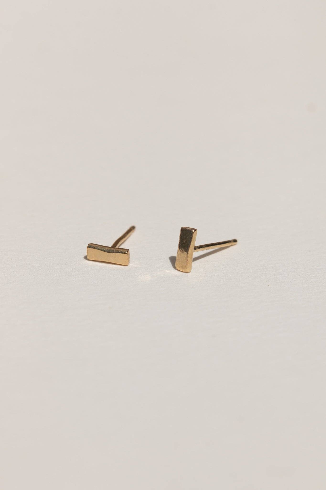 Gold bar stud earrings on a light gray background