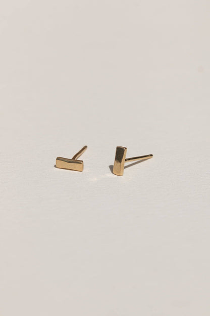 Gold bar stud earrings on a light gray background