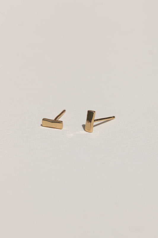 Gold bar stud earrings on a light gray background