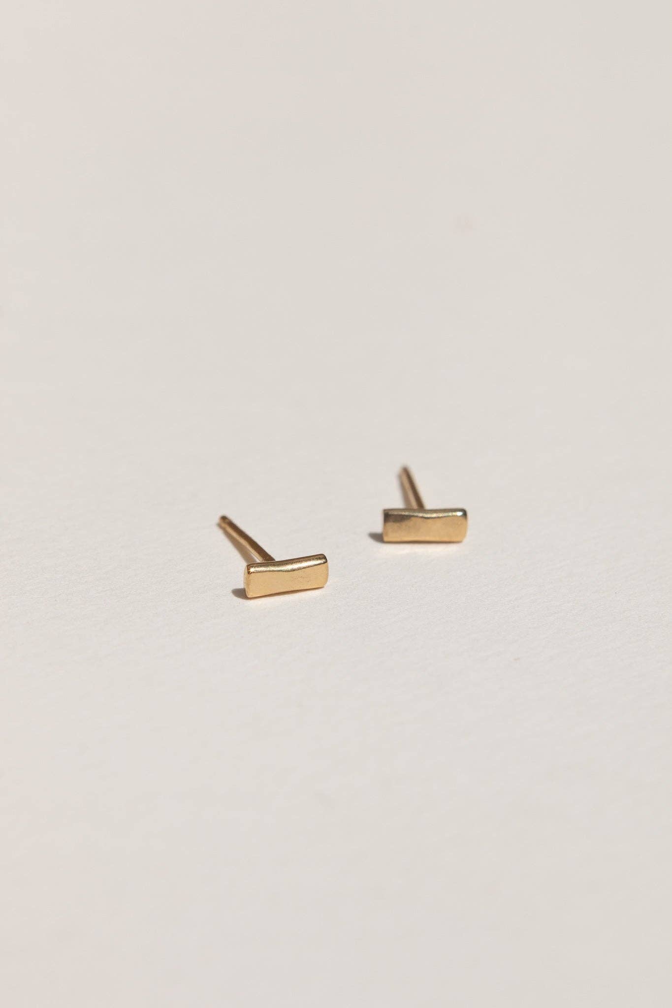 Gold bar stud earrings on a light gray background