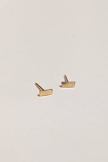 Gold bar stud earrings on a light gray background