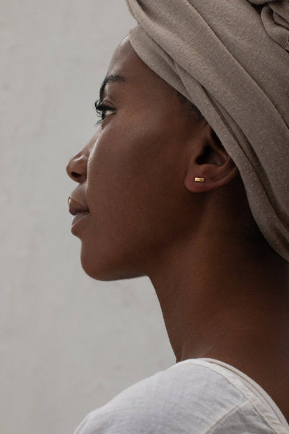 Profile of a woman wearing a beige headscarf against a neutral background