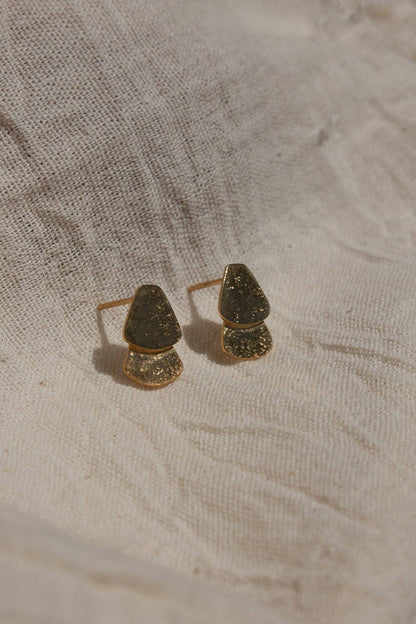 Pair of gold earrings on a textured beige fabric background
