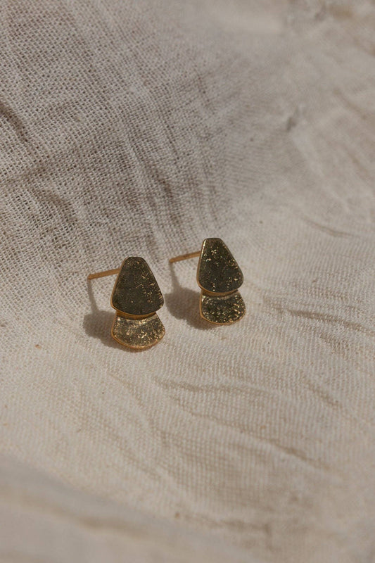 Pair of gold earrings on a textured beige fabric background