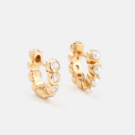 Gold hoop earrings with embedded pearls and small diamonds on a light gray background