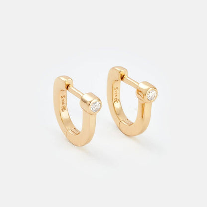 Gold hoop earrings with small diamonds on a light gray background