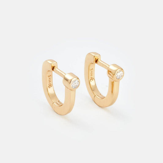 Gold hoop earrings with small diamonds on a light gray background