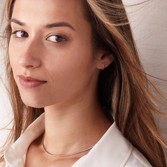 Close-up of a woman wearing a gold earring with a neutral background