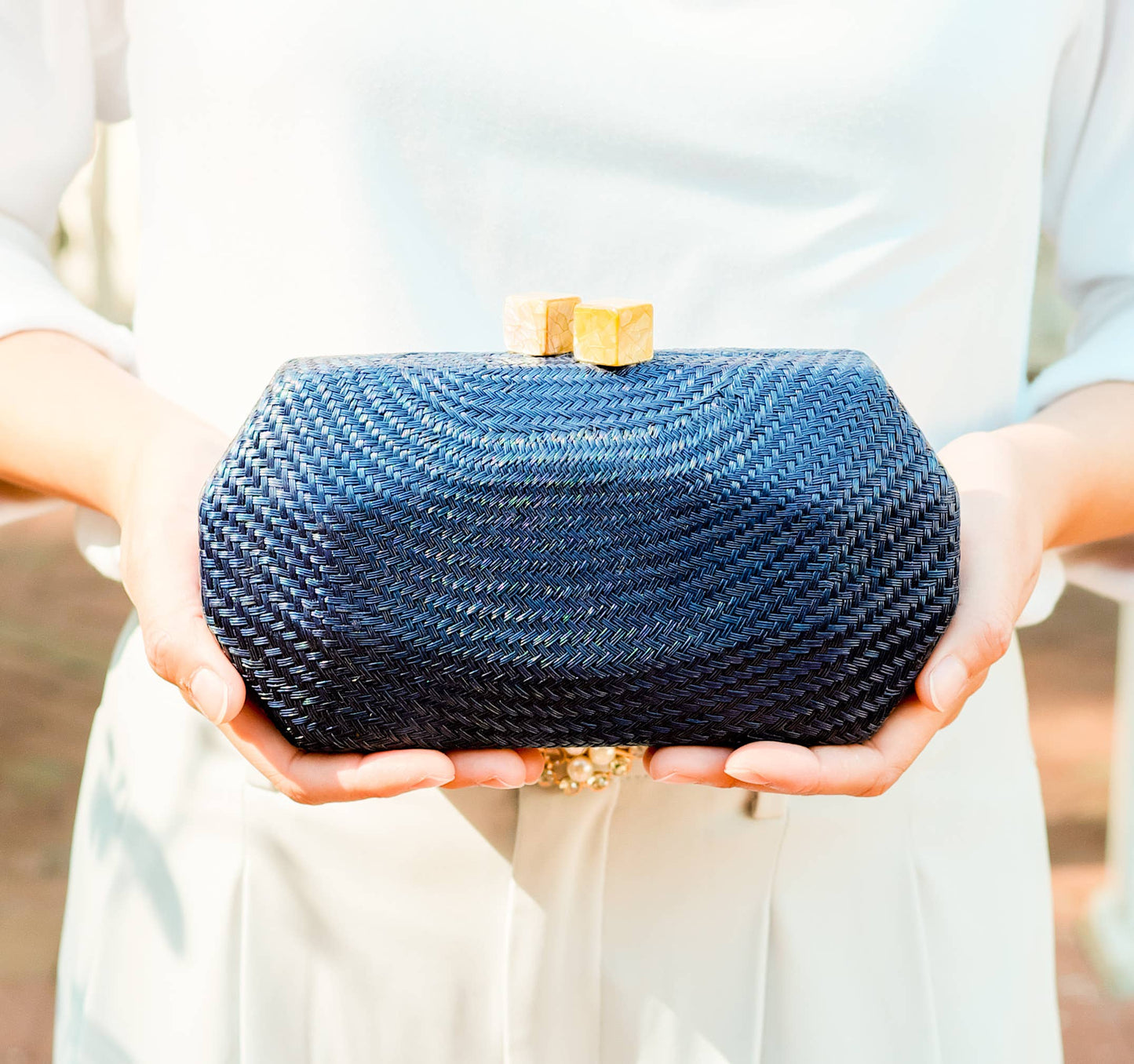 Blue woven clutch held by a person with a blurred background