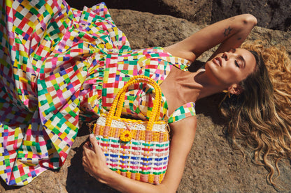 Woman holding a colorful woven bag on a rocky surface