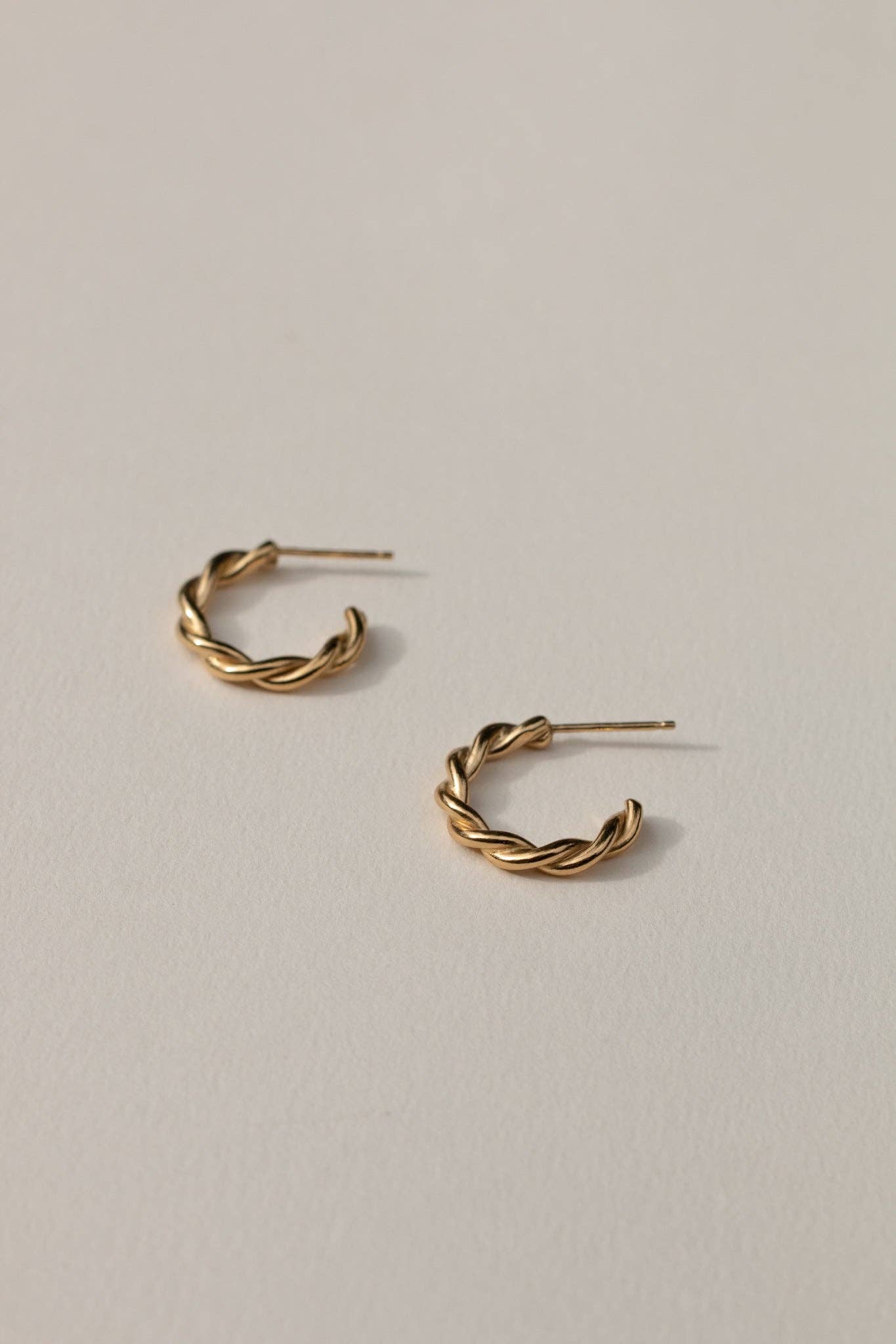 Gold hoop earrings on a light beige background