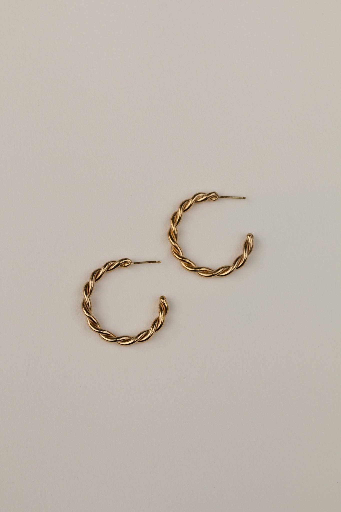 Gold hoop earrings on a light beige background