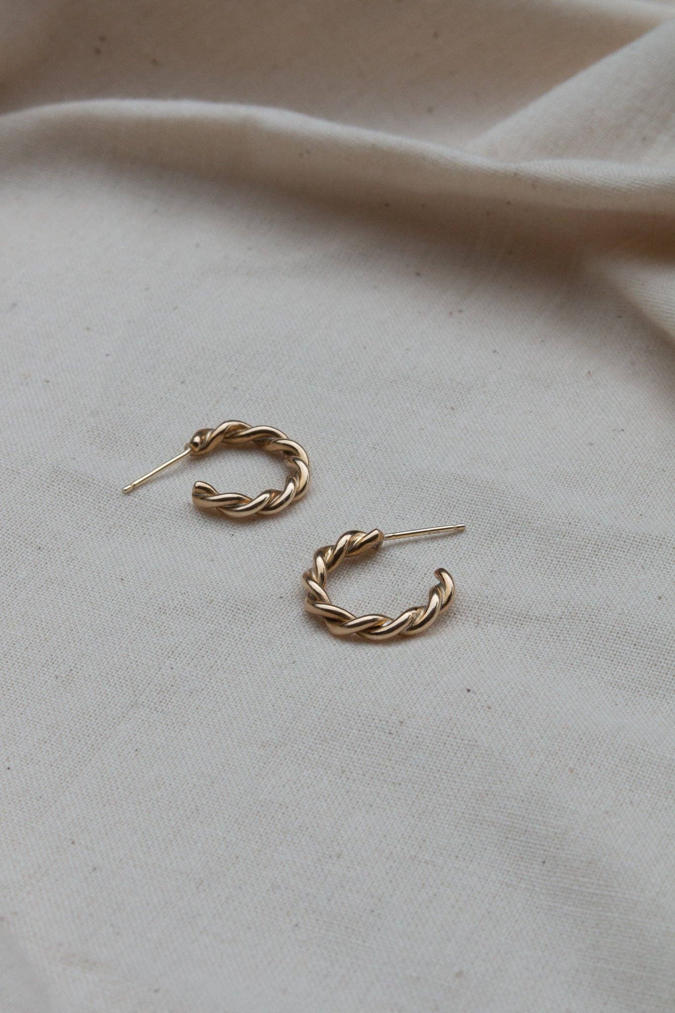 Pair of gold hoop earrings on a beige fabric background